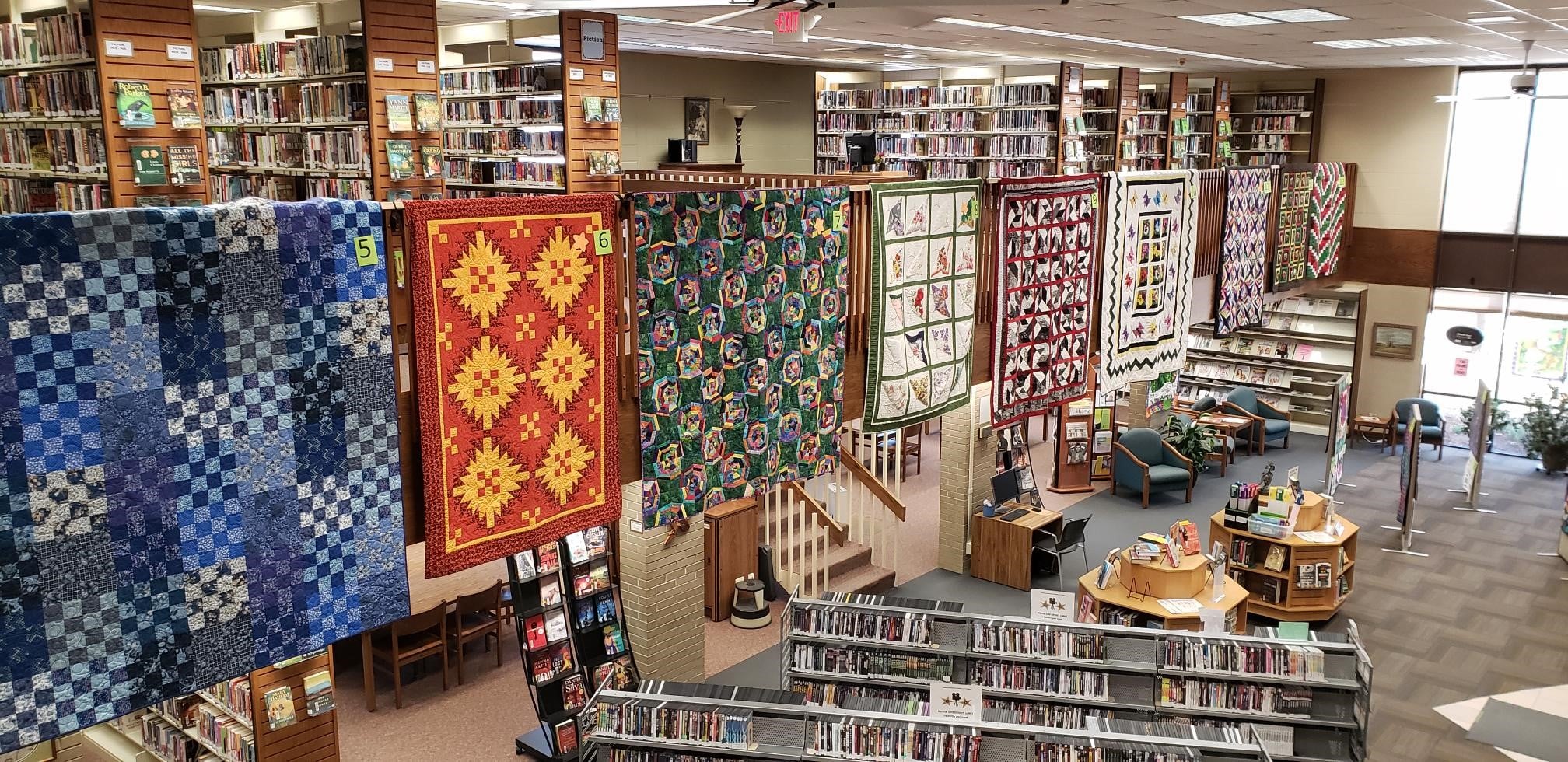 Quilts hanging from the mezzanine banister at the Berlin Public Library.